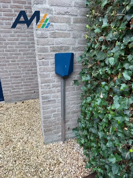 Easee-laadpaal met blauwe cover op een paal, tussen grind en klimop
