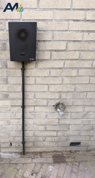Zaptec Go aan een lichte bakstenen gevel, met de kabel in een buis naar beneden