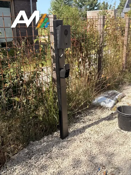 Zaptec Go op een zwarte paal langs een hekwerk
