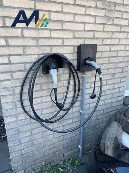 Zaptec Go aan een bakstenen gevel met een kabelhouder en opgerolde laadkabel ernaast