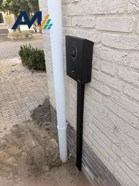 Zaptec Go op een paal tegen een lichte gevel, naast de regenpijp