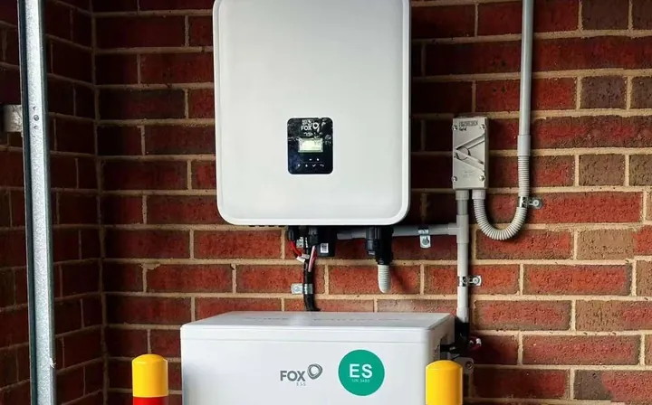 FoxESS EQ-batterij onder een KH-omvormer tegen een rode bakstenen muur