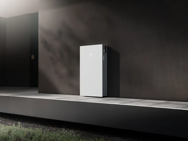 Tesla Powerwall 3P tegen een donkere gevel in de zon