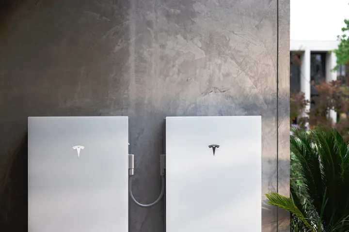 Tesla Powerwall 3P en Expansion naast elkaar aan een betonnen muur