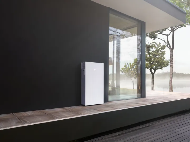 Tesla Powerwall 3P op een houten terras bij een meer