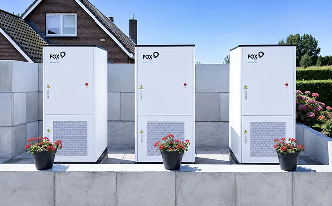 Drie FoxESS G-MAX-kasten op een betonplaat voor een bakstenen gebouw