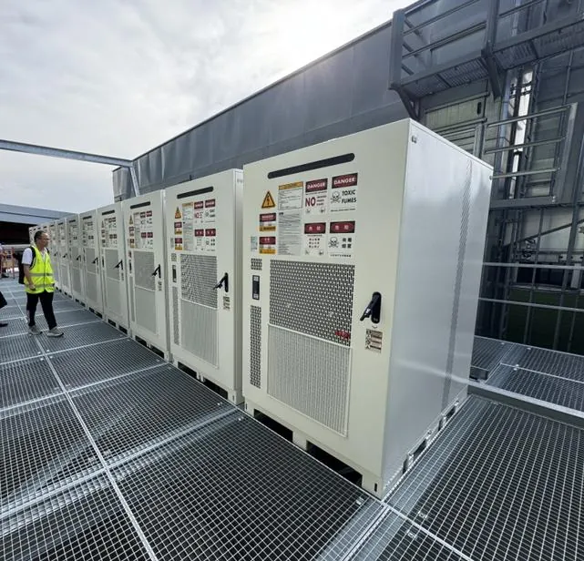 Rij Huawei LUNA2000-215 batterijkasten op een stalen roosterplatform naast een bedrijfshal