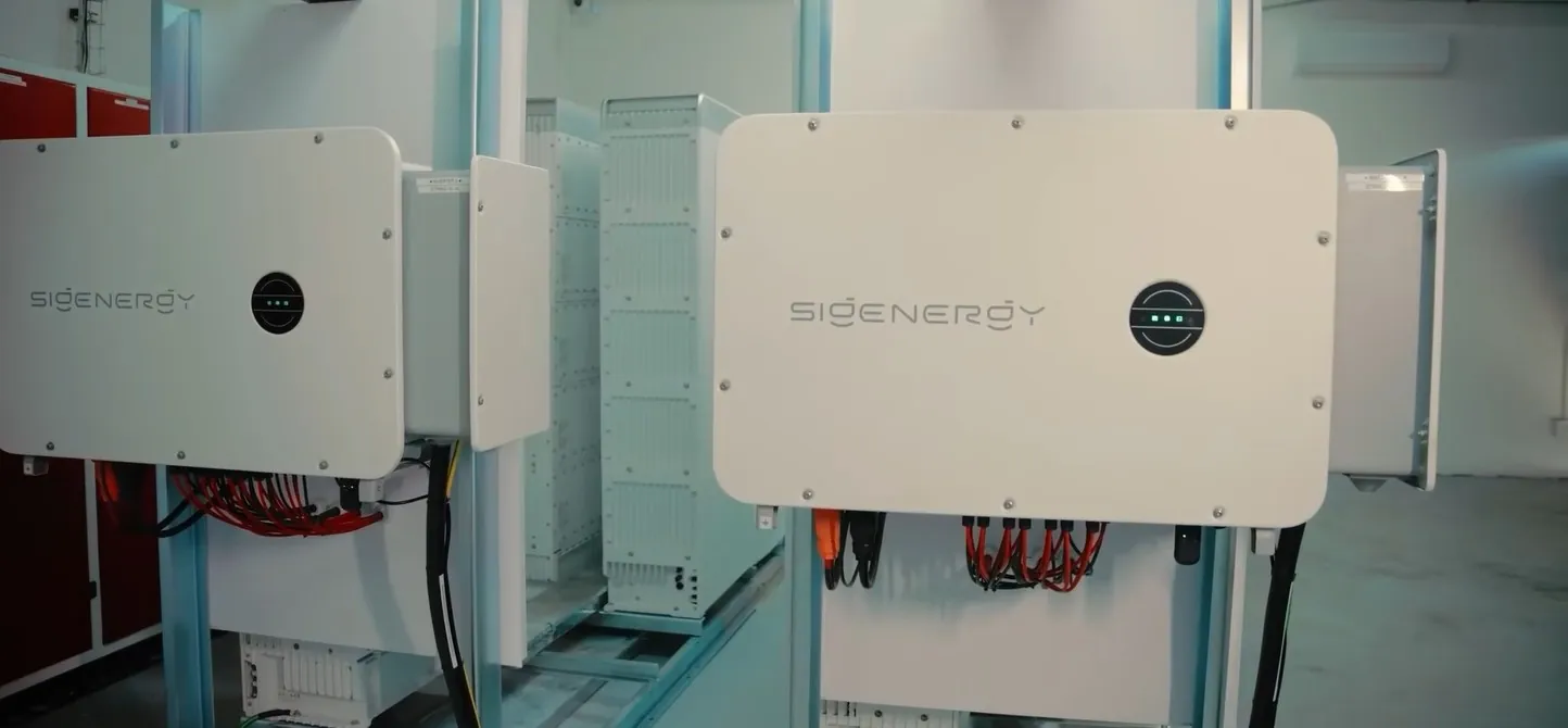Twee Sigen C&I-hybride omvormers op stalen frames in een technische ruimte